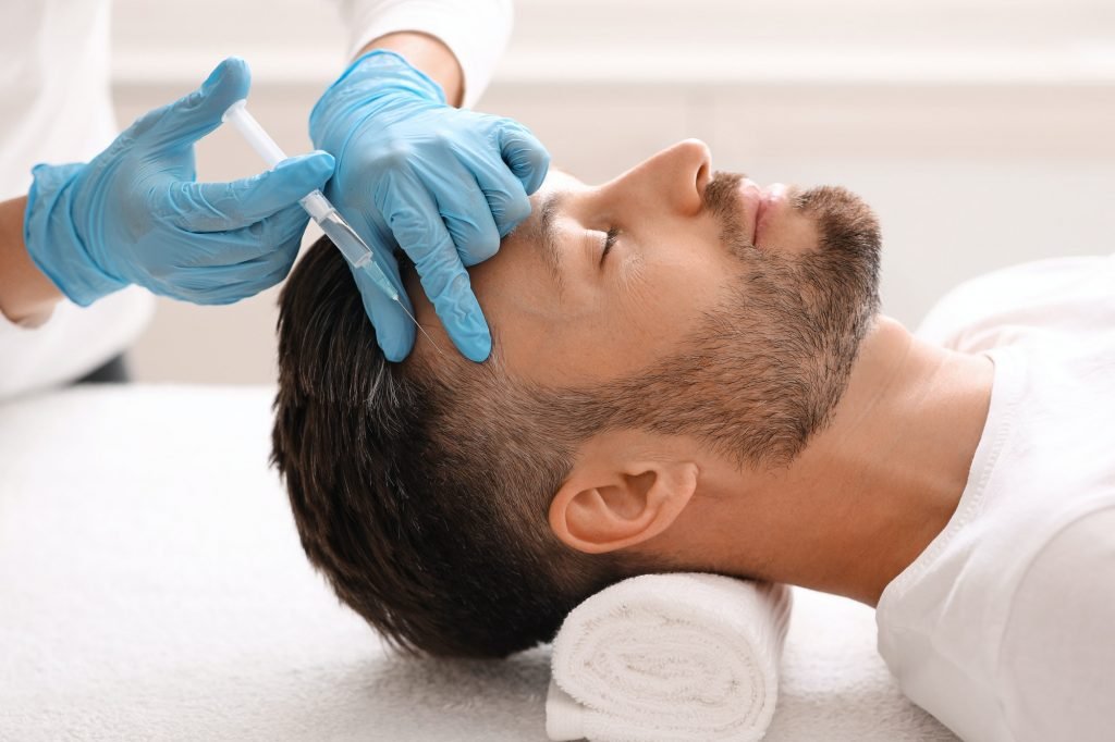 Middle-aged man having hair treatment at clinic